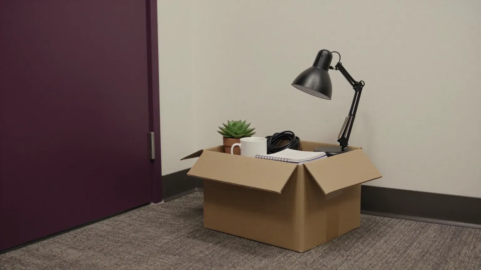 guide header — a cardboard box of desk belongings by a door